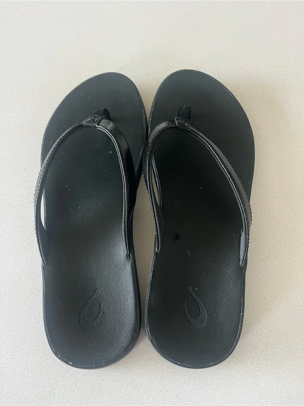 Olukai black flip flops.